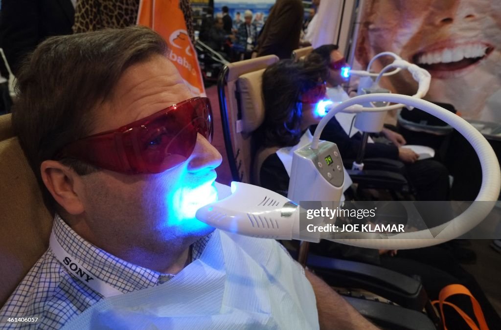 Tooth And Computer A visitor get his teeth whitened at the Teeth Bright booth during the ...
