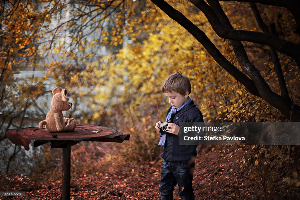 Boy shoots his stuffed toy with film camera
