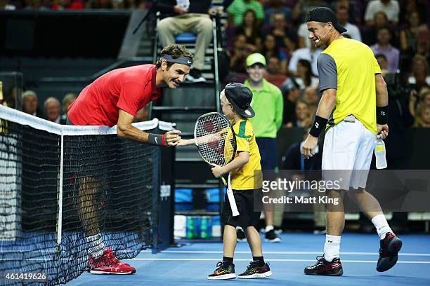 Roger Federer of Switzerland interacts with Lleyton Hewitt's son Cruz Hewitt as Lleyton Hewitt of Australia looks on before their match at Qantas...
