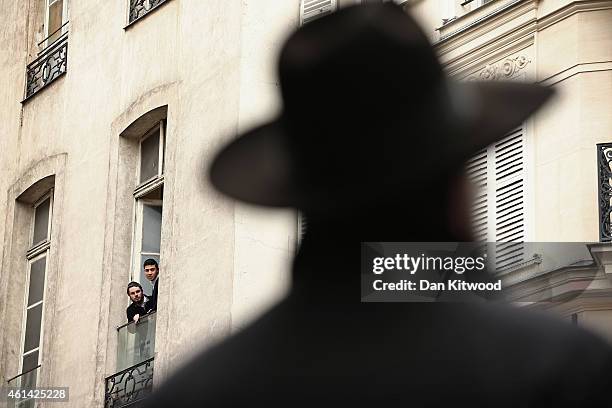 Young Jewish men lean from balconies as the French Interior Minister Bernard Cazeneuve meets police officers after a visit to the school in the...