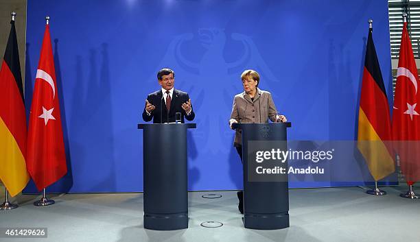 Turkish Prime Minister Ahmet Davutoglu delivers a speech as German Chancellor Angela Merkel listens to him during a joint press conference held after...