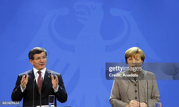 Turkish Prime Minister Ahmet Davutoglu delivers a speech as German Chancellor Angela Merkel listens to him during a joint press conference held after...