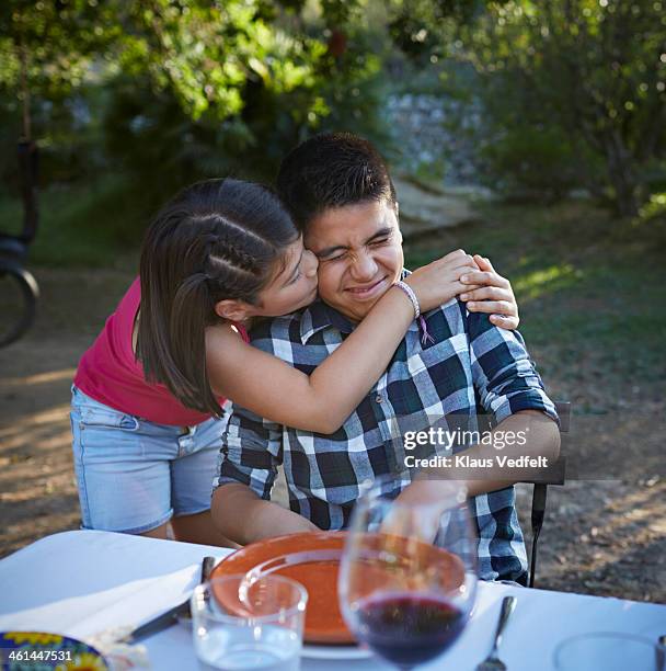 sister kissing her brother on the cheek - awkward dinner imagens e fotografias de stock