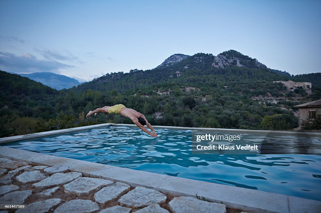 Man jumping in in pool en epic mountain landscape