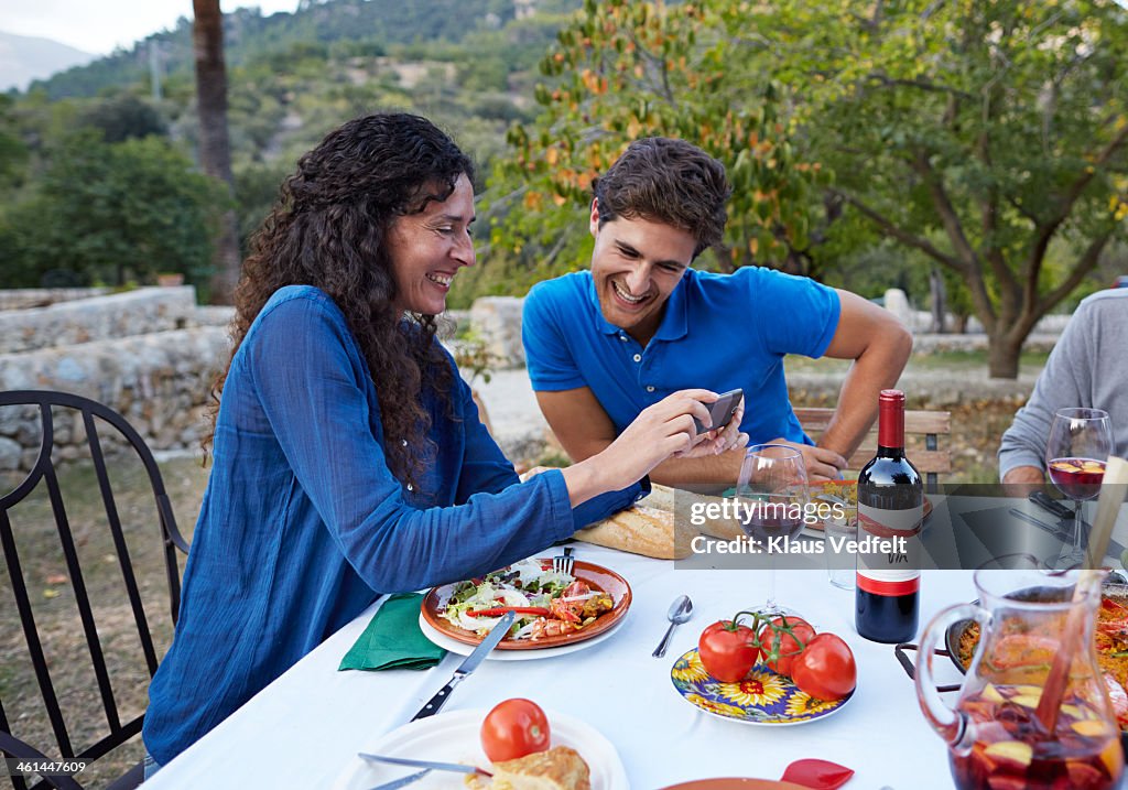 Mother and son looking at phone at family dinner