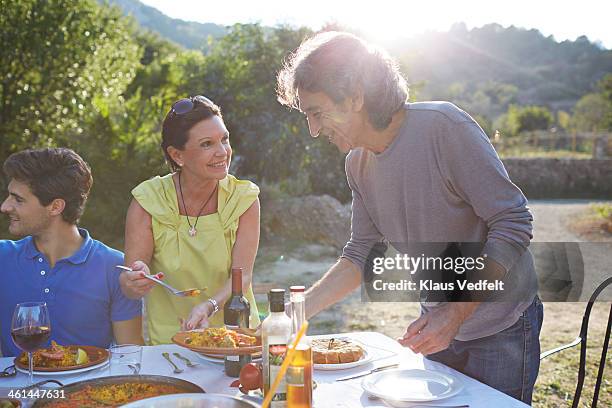 mature couple pouring paella on the plate - paella stock-fotos und bilder
