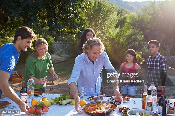 multigenerational family setting dinner table - big family dinner stock pictures, royalty-free photos & images