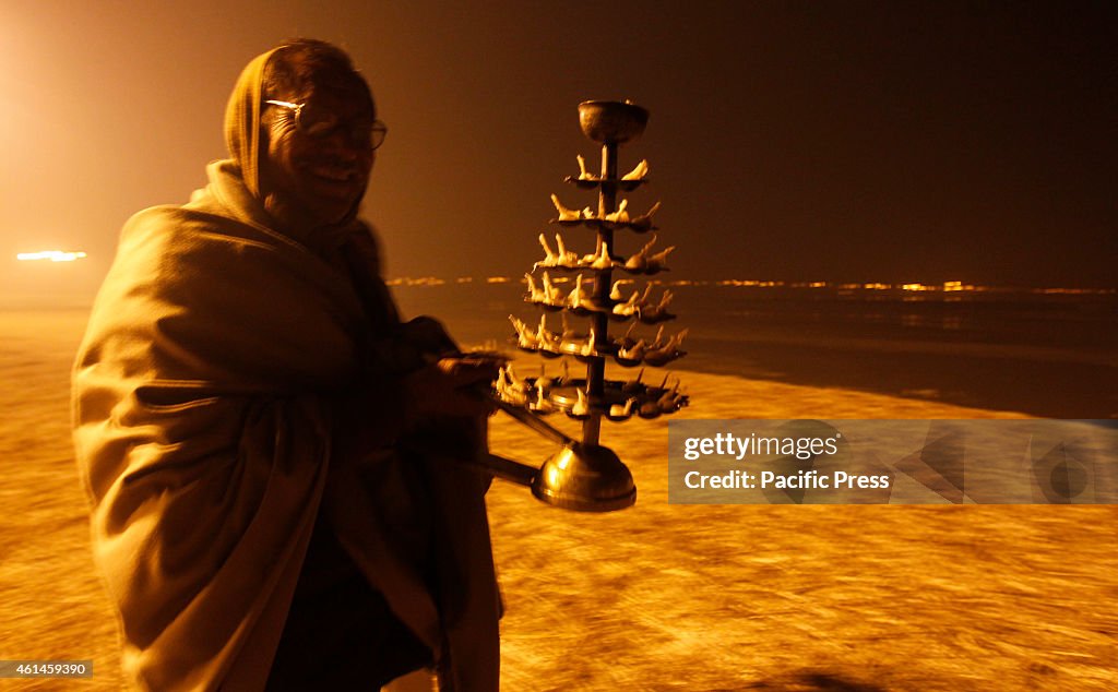 A Hindu man performs oil lamp prayer at the river bank of...