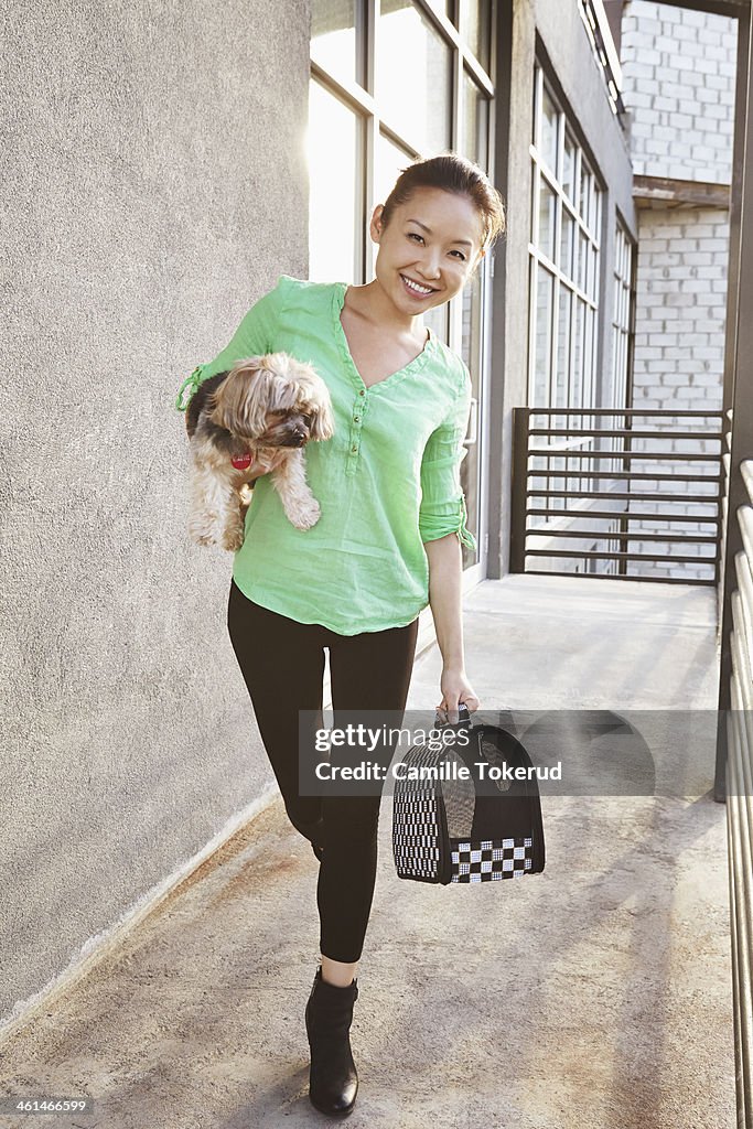 Young woman holding dog and smiling