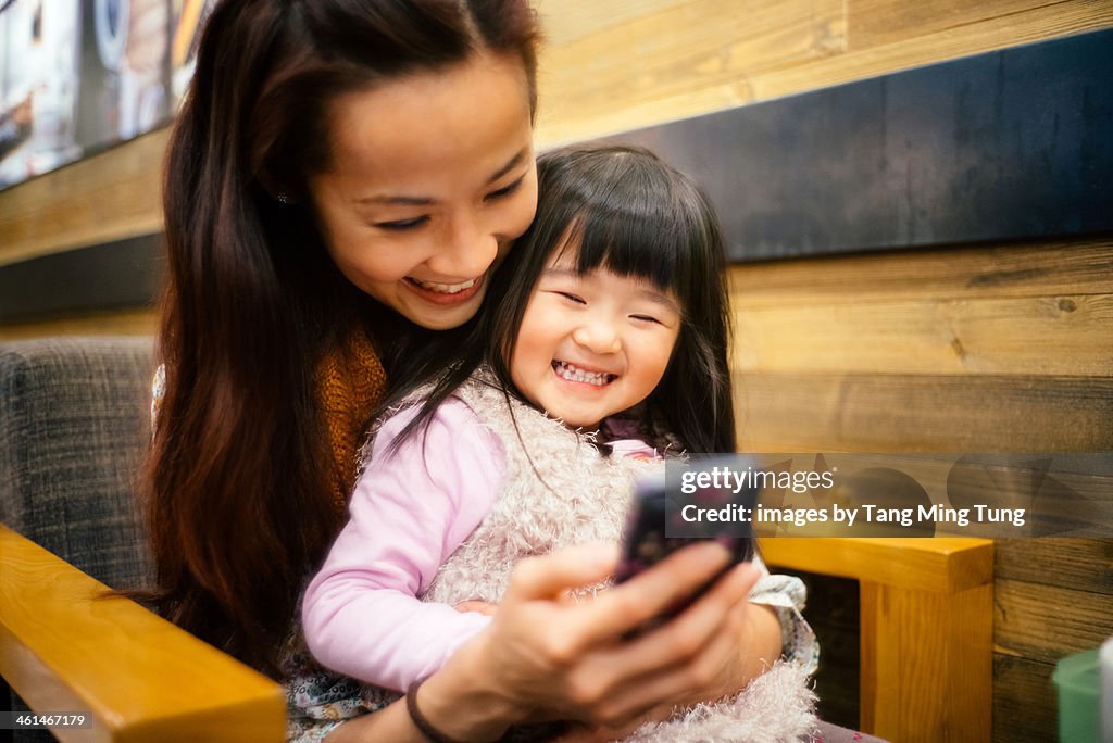 Mom & toddler girl using smartphone joyfully