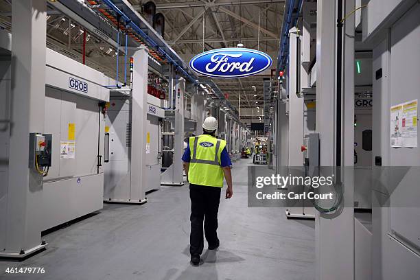 An employee walks past a Ford logo in the yet-to-be-completed engine production line at a Ford factory on January 13, 2015 in Dagenham, England....