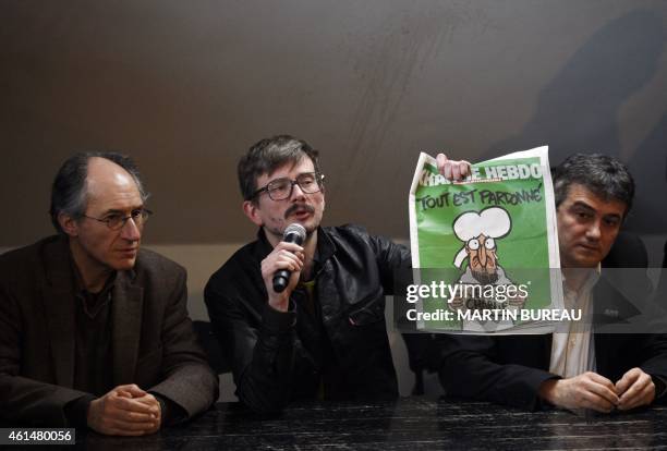 French cartoonist Renald Luzier, aka Luz , holds up the new issue of French satirical weekly Charlie Hebdo, flanked by editor in chief of Charlie...