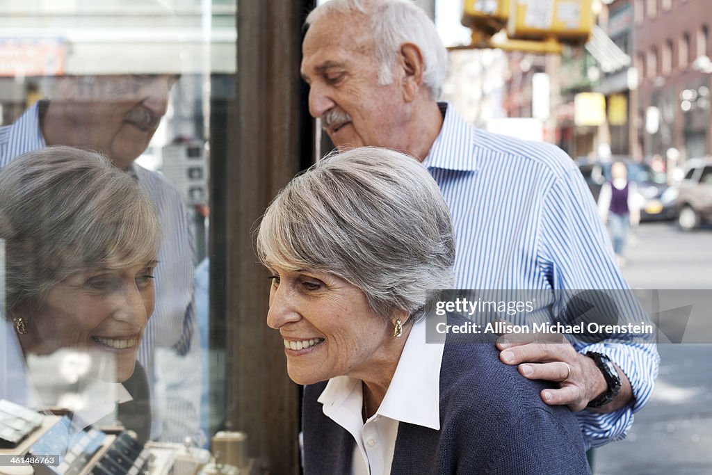 Senior couple looking at jewelry in shop window