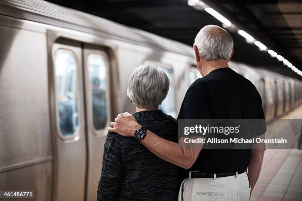 senior couple waiting for train in city - man woman train station stockfoto's en -beelden