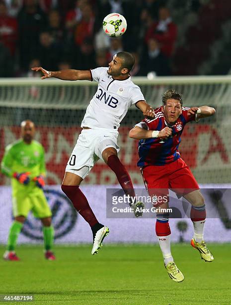 Hamdi Harbaoui of Qatar Stars outjumps Bastian Schweinsteiger of Muenchen during a friendly match between FC Bayern Muenchen and Qatar Stars at...