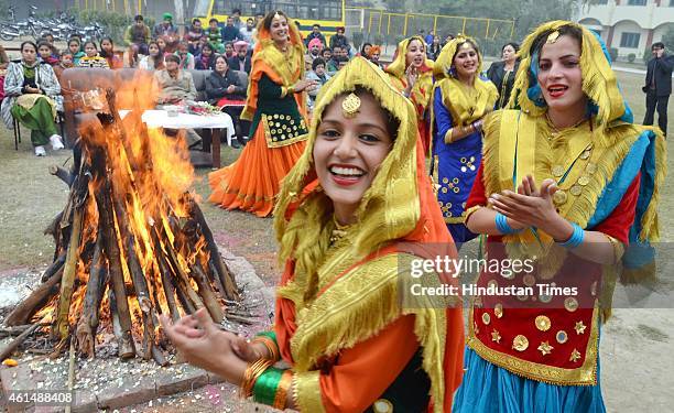 School girls wearing traditional Punjabi dresses perform Giddha dance around bonfire on the occasion of Lohri festival at Shahzada Nand College on...