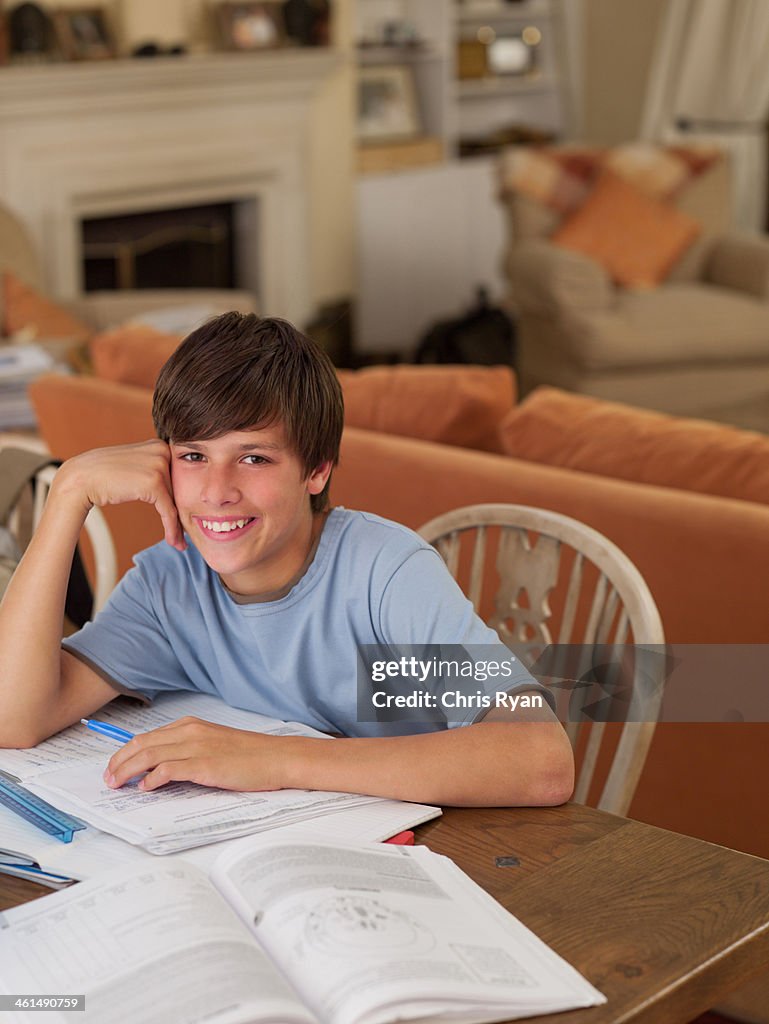 Boy sitting at table with homework smiling