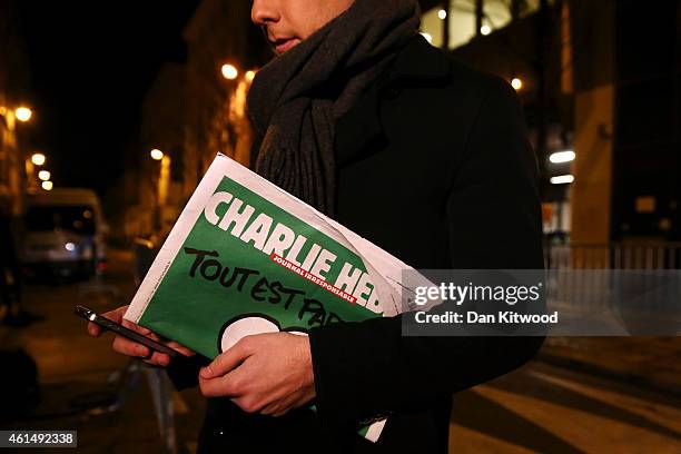 Journalist holds an early copy of a Charlie Hebdo magazine while delivering a news report outside the offices of Liberation Newspaper Group on...