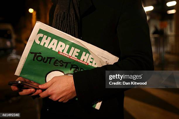 Journalist holds an early copy of a Charlie Hebdo magazine while delivering a news report outside the offices of Liberation Newspaper Group on...