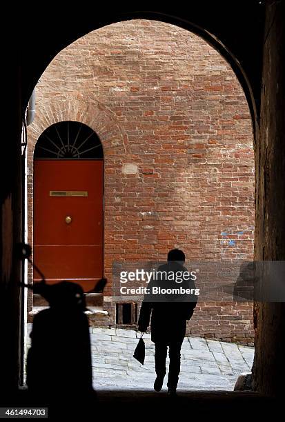 Pedestrian walks through an archway above a cobbled street in Siena, Italy, on Wednesday, Jan. 8, 2014. Banca Monte dei Paschi di Siena SpA, the...