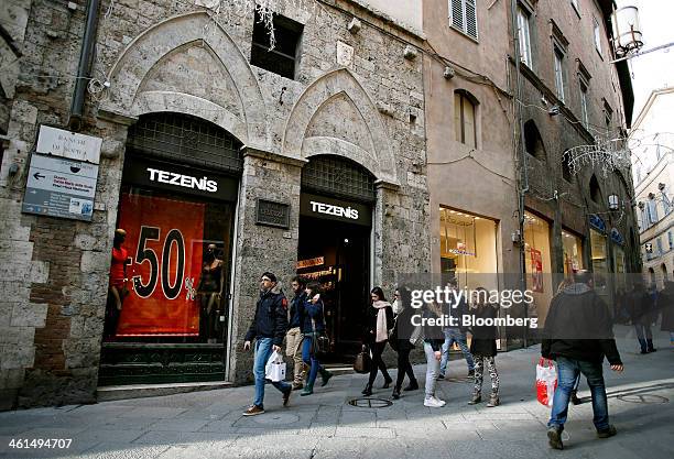 Pedestrians pass clothes stores advertising sales in their window displays in Siena, Italy, on Wednesday, Jan. 8, 2014. Banca Monte dei Paschi di...