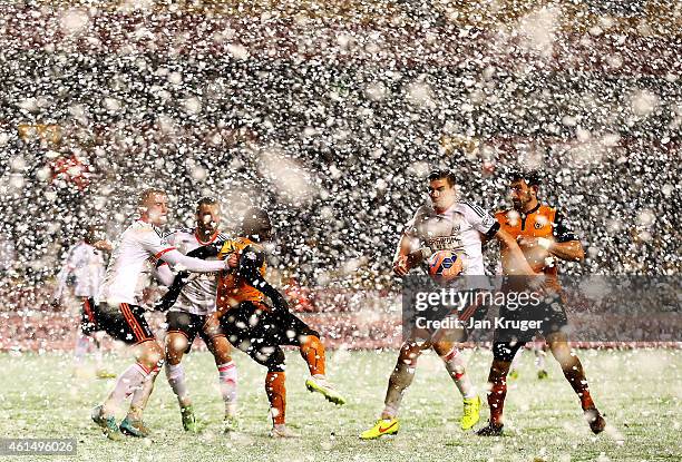 Players battle for the ball as snow falls during the FA Cup third round replay match between Wolverhampton Wanderers and Fulham at Molineux on...