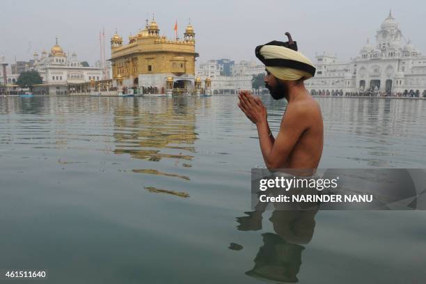 An Indian Sikh devotee prays as he takes a dip in the holy sarover during the Maghi Mela at the Sikh Shrine Golden Temple in Amritsar on January 14,...