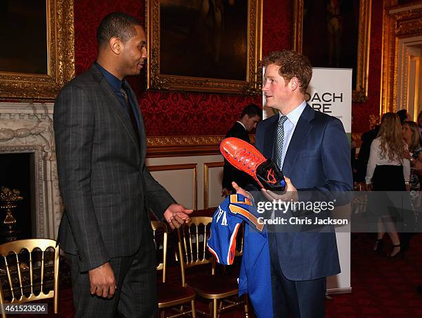 Prince Harry is presented with a basketball shirt and size 15 basketball shoe by NBA All-Star Carmelo Anthony during a Coach-Core Graduation event at...