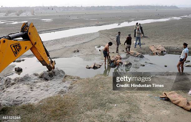 Government staff removing the dead human bodies that are found floating in Ganga river near Pariyar on January 14, 2014 in Unnao, India. In a curious...