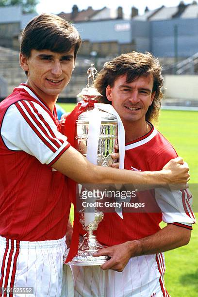 Arsenal forwards Alan Smith and Charlie Nicholas pictured with the previous seasons silverware, the League Cup, before the start of the 1987/88...