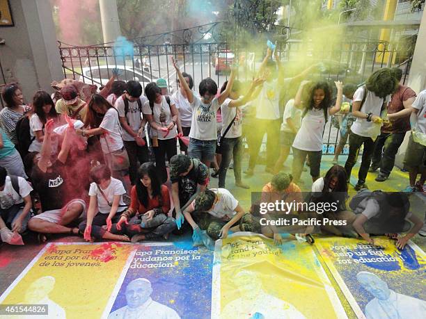 Activists throw colored powder into the air in front of the University of Santo Tomas to celebrate the oncoming visit of Pope Francis to the country....