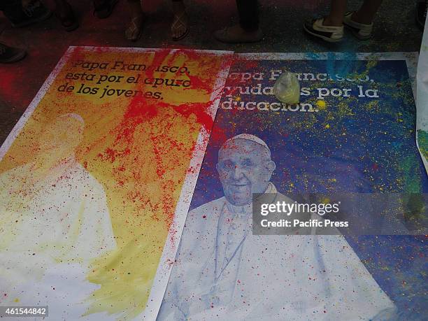 Colored powder lies on top of tarpaulins containing the image of Pope Francis along with messages in Spanish, in front of the University of Santo...