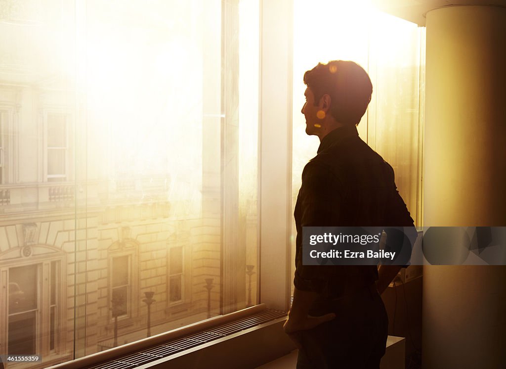 Businessman looking out over the city at sunrise.