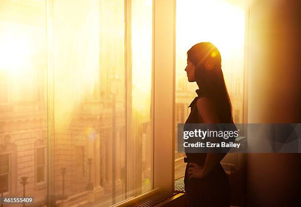 business woman looking over the city at sunrise. - looking through window stockfoto's en -beelden