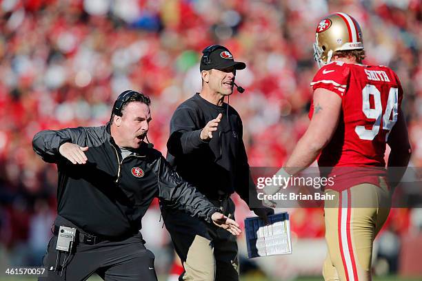 Defensive line coach Jim Tomsula and head coach Jim Harbaugh congratulate defensive tackle Justin Smith of the San Francisco 49ers after a sack on...