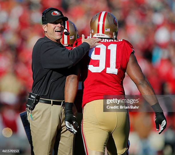 Defensive tackle Ray McDonald of the San Francisco 49ers gets congratulated by head coach Jim Harbaugh after sacking quarterback Russell Wilson of...