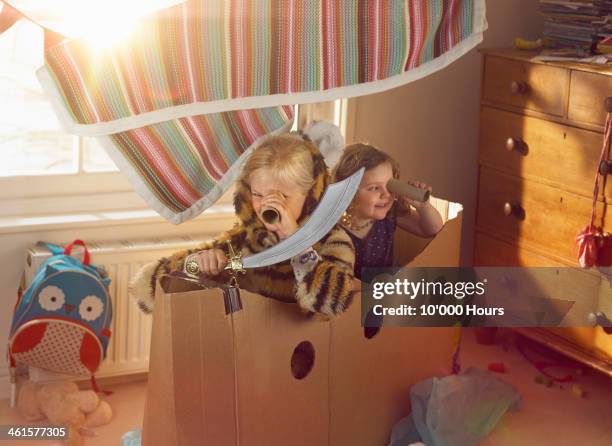 two young girls playing a home made cardboard boat - child playing stock-fotos und bilder