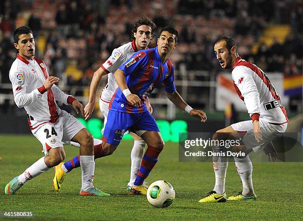 Angel Rodriguez of Levante UD is flanked by Iago Falque and Alejandro Galvez of Rayo Vallecano de Madrid during the Copa del Rey Round of 16, 1st Leg...