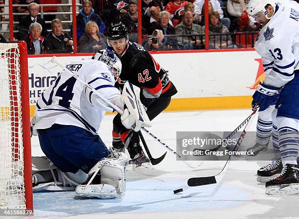 Nazem Kadri of the Toronto Maple Leafs attempts to clear the puck as James Reimer defends the net against Brett Sutter of the Carolina Hurricanes...