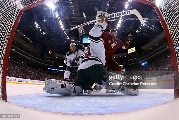 Goaltender Niklas Backstrom of the Minnesota Wild turns to make a play on the puck as Martin Hanzal of the Phoenix Coyotes skates in alongside Ryan...