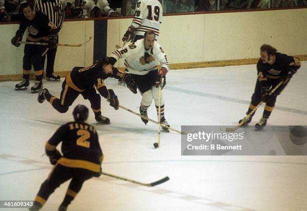 Bill White of the Chicago Blackhawks skates with the puck as he is defended by Butch Goring, Terry Harper and Don Kozak of the Los Angeles Kings...