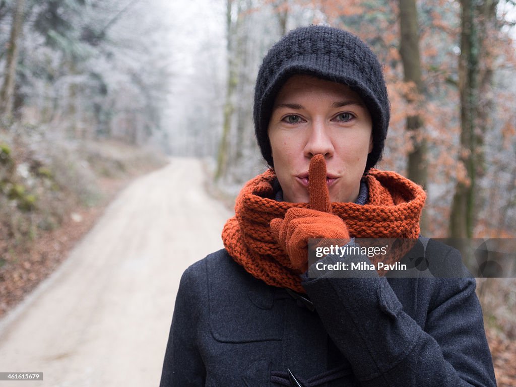 Woman makes be quite expression in foggy woods