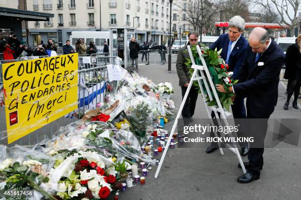 Secretary of State John Kerry and French Foreign Affairs minister Laurent Fabius lay a wreath of flower in front of a placard reading "Brave Police...