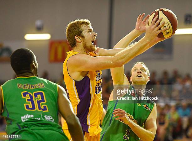 Tom Garlepp of the Kings attempts a layup past Jacob Holmes and Mickell Gladness of the Crocodiles during the round 15 NBL match between the...