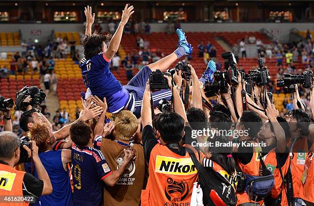 Yashuhito Endo of Japan is thrown into the air by team mates in celebration of his 150th game for Japan during the 2015 Asian Cup match between Iraq...