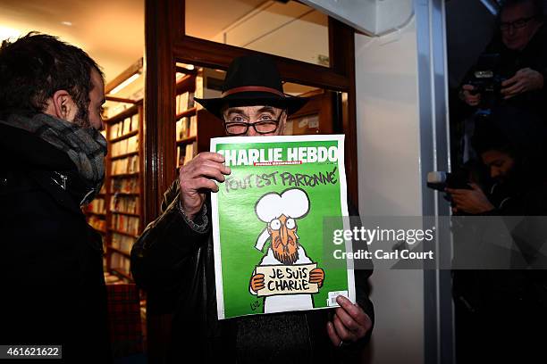 Man holds up a copy of Charlie Hebdo magazine as he leaves a French bookstore on January 16, 2015 in London, England. People queued since the early...