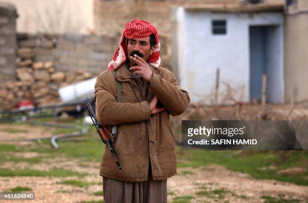 An armed Yazidi man smokes a cigarette on January 15, 2015 in the village of Sinoni in the northern Iraqi district of Sinjar, which Iraqi Kurdish...