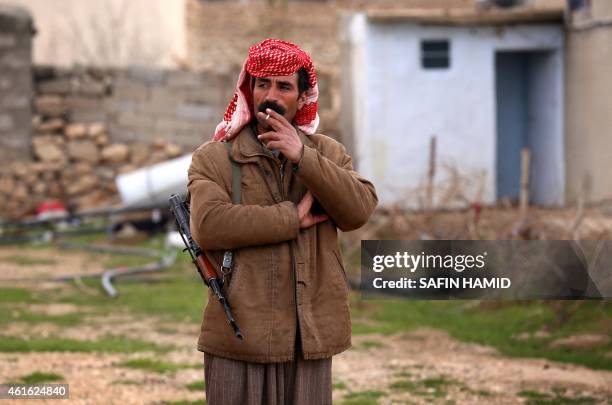 An armed Yazidi man smokes a cigarette on January 15, 2015 in the village of Sinoni in the northern Iraqi district of Sinjar, which Iraqi Kurdish...