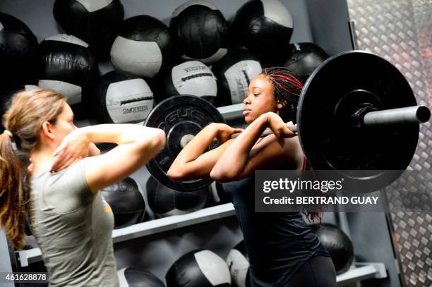 Woman lifts weight during a crossfit training in a gym in Paris on January 16, 2015. AFP PHOTO / BERTRAND GUAY