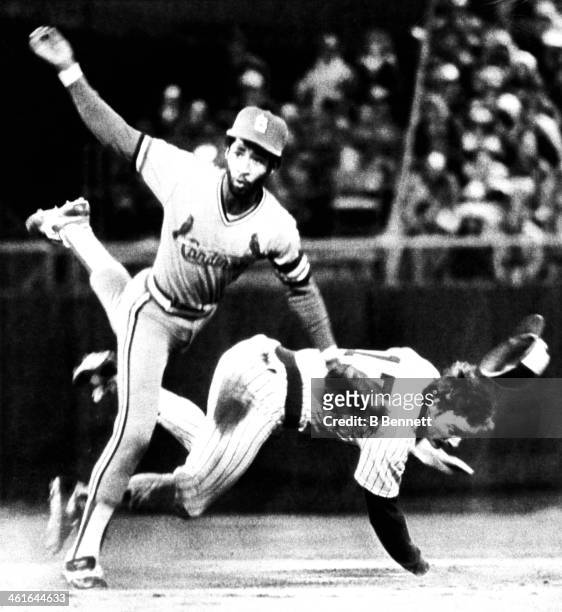 Shortstop Ozzie Smith of the St. Louis Cardinals turns the double play as Jim Gantner of the Milwaukee Brewers tries to break it up during Game 3 of...